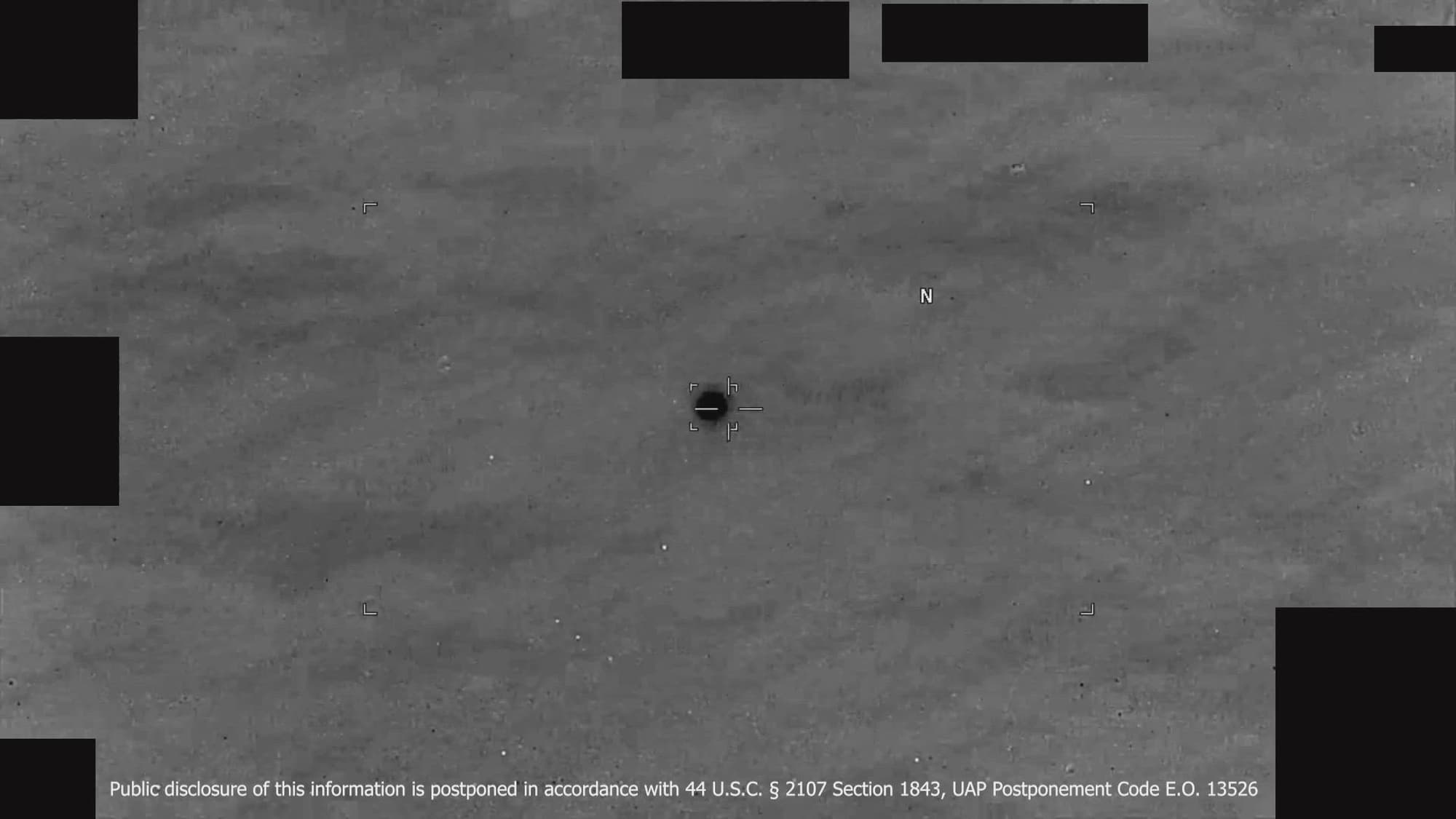 DOW-UAP-PR143 — a frame from a U.S. Indo-Pacific Command infrared sensor video over the Yellow Sea in 2023: a single dark, black-hot object centred under the sensor's tracking reticle against grey open water, with the Department of War's redaction boxes at the frame edges. Released in PURSUE Release 06 on September 18, 2026.